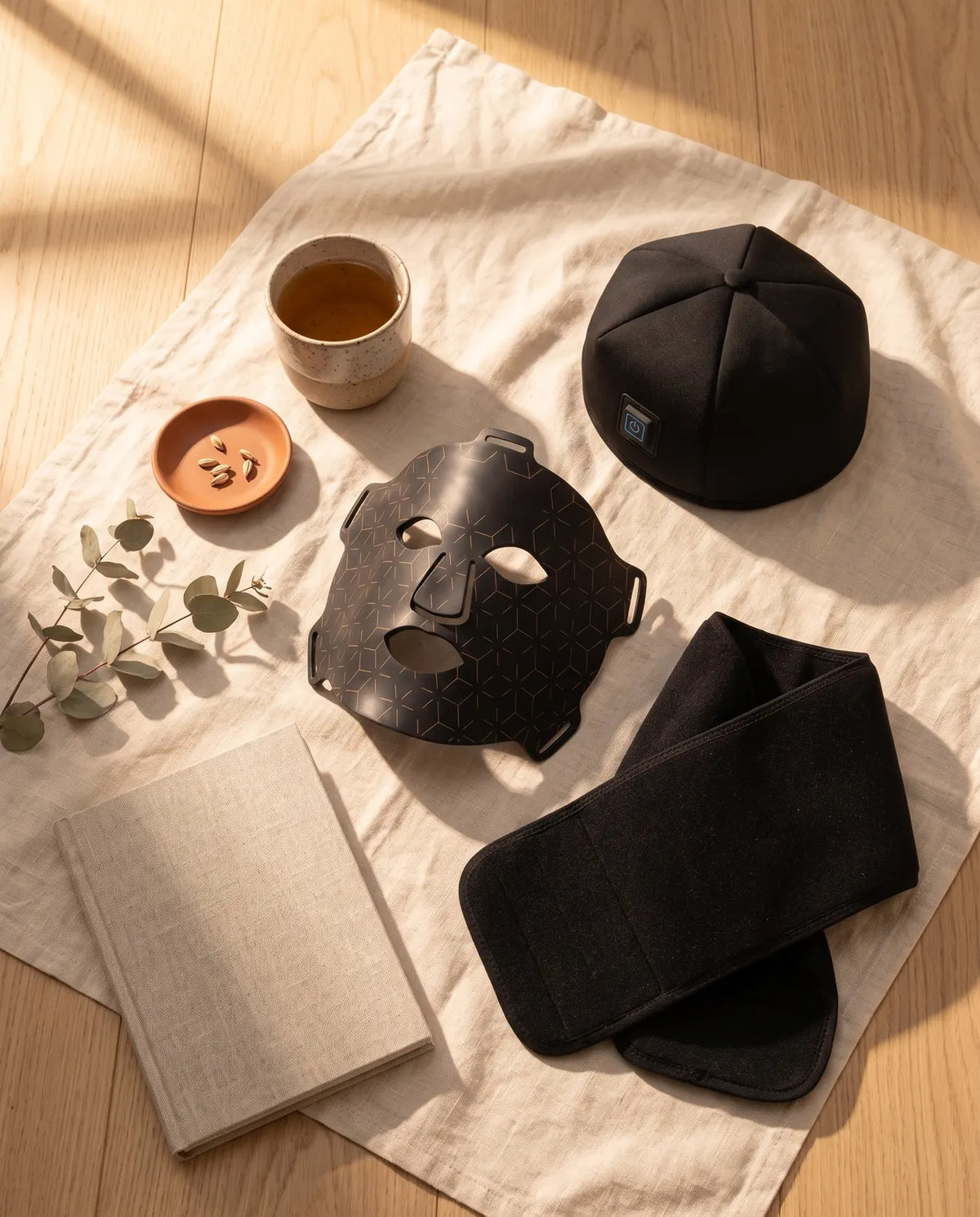 Clinirae Light Mask, Scalp Light Cap and Light Wrap on cream linen with tea and eucalyptus