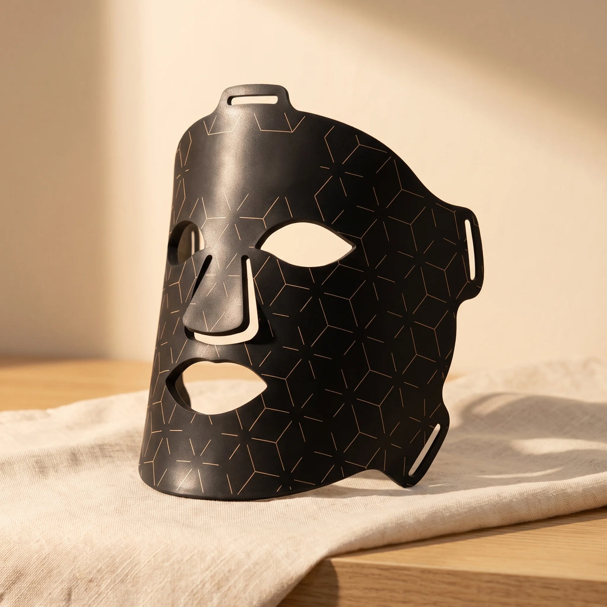 Clinirae Light Mask, flexible black LED face mask, on cream linen
