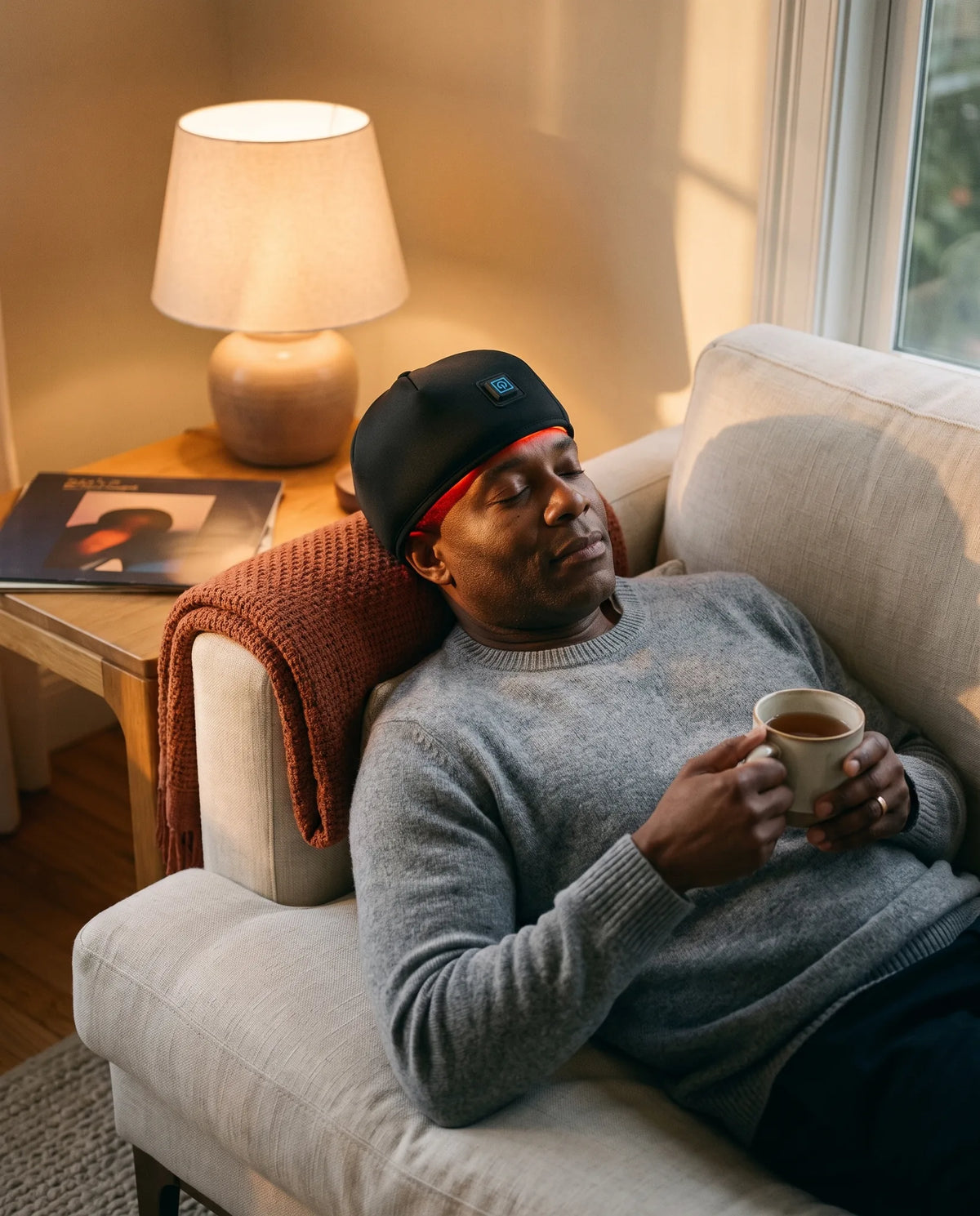 Man relaxing on a sofa wearing the Clinirae Scalp Light Cap
